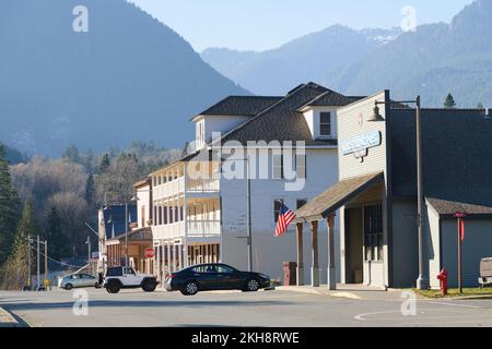 Skykomish, WA, USA - 18. November 2022; Blick in Richtung Westen entlang der Railroad Avenue in Skykomish mit ortsansässigen Unternehmen und Bergen Stockfoto