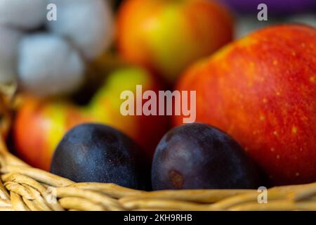 Zwei reife Pflaumen, Nahaufnahme auf einem Hintergrund mit roten Äpfeln. Selektiver Fokus Stockfoto