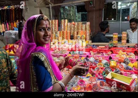 Jodhpur, Rajasthan, Indien - 18.10.2019 : lächelnde Rajasthani-Frau, die farbenfrohe Armreifen ausprobiert. Armreifen werden auf dem berühmten Sardar Markt und Ghanta g verkauft Stockfoto