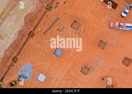 Auf großen Baustellen werden Gräben für das Gießen von Beton in Fundamente im Rahmen eines größeren Bauprojekts vorbereitet Stockfoto