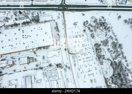 Parkplatz im Industriegebiet. Reihen von Autos, die mit Schnee bedeckt sind. Draufsicht. Stockfoto