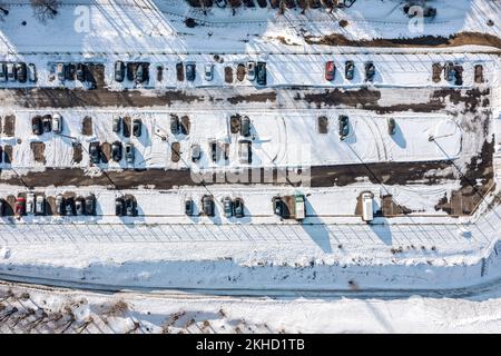 Schneebedeckter Außenparkplatz mit Autos. Luftaufnahme an sonnigen Wintertagen. Stockfoto