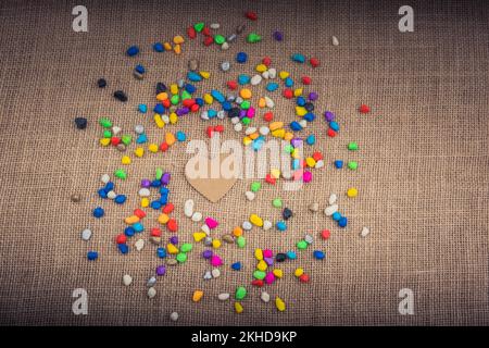 Herz aus Papier inmitten der bunten Steinchen auf Leinwand Boden Stockfoto