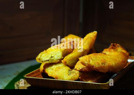 Pisang Goreng oder Bananenpfannkuchen aus Indonesien, serviert auf Holzteller. Stockfoto