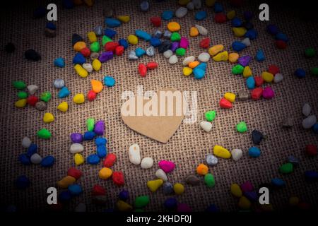 Herz aus Papier inmitten der bunten Steinchen auf Leinwand Boden Stockfoto