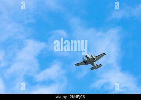 Ein zweimotoriges Flugzeug fliegt durch den blauen Himmel.