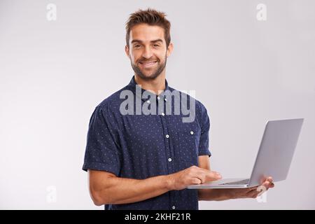 Er ist ein leidenschaftlicher Blogger. Ein Studiofoto eines gutaussehenden Mannes mit einem Laptop. Stockfoto