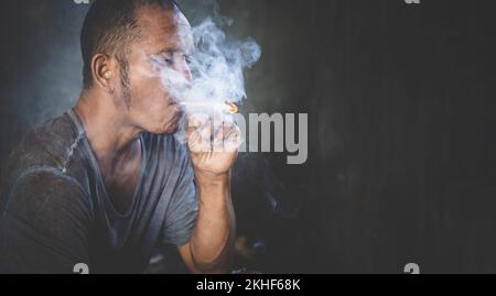 Ein Mann raucht Gras, Cannabis, einen Joint. Rauch auf schwarzem Hintergrund. Konzepte der medizinischen Marihuana-Verwendung und Legalisierung des Cannabis. Rauchen, Welt und Stockfoto