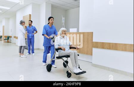 Asiatische Krankenschwester, die behinderte ältere Frauen im Rollstuhl im Krankenhaus betreut Stockfoto