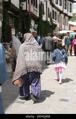 Straßenszene mit Marktständen, Haupteinkaufsstraße, Beypazari, Türkei; Fußgänger; Frau in türkischer Traditioanl-Hose und Schal Stockfoto