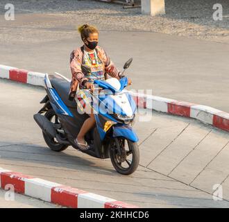 SAMUT PRAKAN, THAILAND, MÄRZ 02 2022, Eine Frau mit Gesichtsmaske fährt ein Motorrad Stockfoto