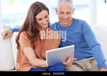 Zeit online teilen. Ein glückliches Paar zu Hause, das sein digitales Tablet zusammen verwendet. Stockfoto