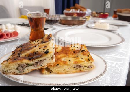 Nahaufnahme des türkischen Patty namens Su borek mit Fleisch. Traditioneller Frühstückstisch mit Tee im Glas. Köstliches Konzept für das Mittagessen am Morgen. Stockfoto