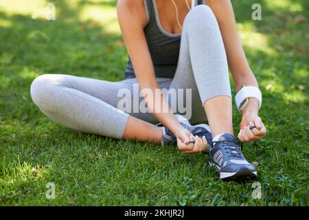 Mit einem Workout verbunden. Eine Läuferin, die ihre Schnürsenkel bindet. Stockfoto