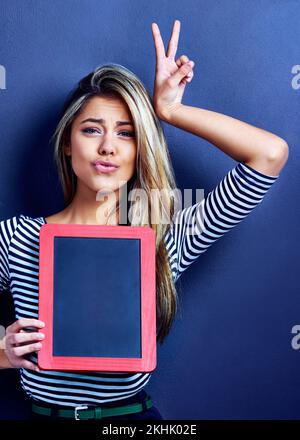 Eine verspielte Botschaft. Eine verspielte junge Frau mit einer Tafel. Stockfoto