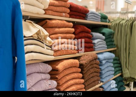 Nahaufnahme der Regale mit bunten Pullover im Einkaufszentrum. Einkaufskonzept, Isolierung für Herbst und Winter Stockfoto