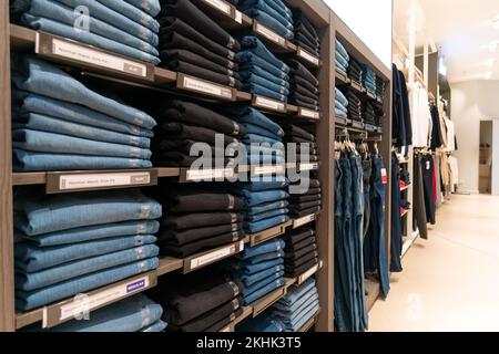 Nahaufnahme von vielen Jeans in den Regalen im Laden. Ein Haufen Jeans auf dem Regal. Konzept des Einkaufs, Verkaufs, Einkaufs und Jeans. Stockfoto