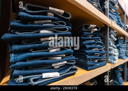 Nahaufnahme von vielen Jeans in den Regalen im Laden. Ein Haufen Jeans auf dem Regal. Konzept des Einkaufs, Verkaufs, Einkaufs und Jeans. Stockfoto