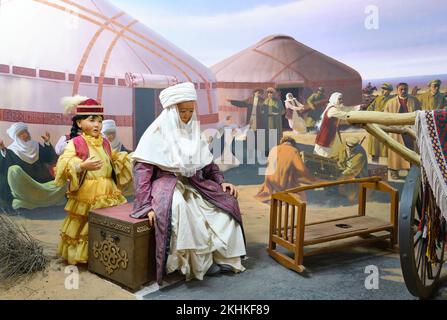 Ein Diorama aus einer Seidenstraße-Ära, einer kasachischen Familie, Frau und Tochter, die warten, während der Vater ein Wagenrad repariert. Im Museum für die Opfer von Politi Stockfoto