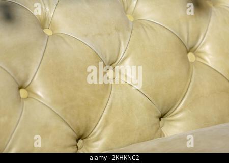 Ledermöbel. Gepolsterte Lederknöpfe mit Kontrastnähten. Makrostruktur gesteppter Lederpolster mit Möbelnägeln. Weicher, leichter Litze Stockfoto