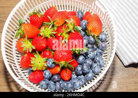 Nahaufnahme von leuchtend roten, saftigen Erdbeeren und Blaubeeren auf dem Tisch Stockfoto
