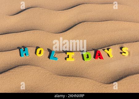 Feiertage auf hölzernen Buchstaben geschrieben auf Sand einer Düne Stockfoto