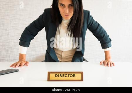 Junge, weiße, brünette Geschäftsfrau, Regisseurin im Büro, stehen auf, wütendes Gesicht, Druck zeigen, schauen Sie sich Kamera pov an. Wütender Regisseur im Büro, von dem er wütete Stockfoto