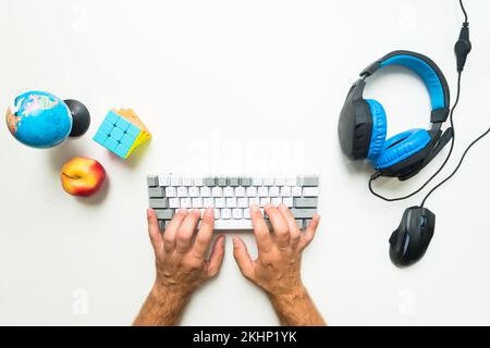 Top-Gamer-Konzept mit Tastatur für Erwachsene, Ansicht von oben, Spielausrüstung, Maus, Tastatur, Headset, auf weißem Tischhintergrund mit Platz zum Kopieren Stockfoto