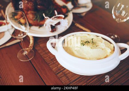 Essen, Kartoffelbrei und Esstisch für Thanksgiving oder Weihnachtsfeier mit Hausmannskost zum Mittag- oder Abendessen. Kartoffelpüree Stockfoto