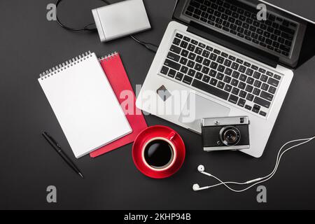 Ein Notebook auf einem schwarzen Desktop mit einer Tasse Kaffee, einem Telefon und einem wi-Fi-Schild, arbeiten Sie in sozialen Netzwerken. Draufsicht. Hochwertiges Foto Stockfoto