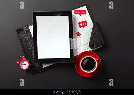 Ein Notebook auf einem schwarzen Desktop mit einer Tasse Kaffee, einem Telefon und einem wi-Fi-Schild, arbeiten Sie in sozialen Netzwerken. Draufsicht. Hochwertiges Foto Stockfoto