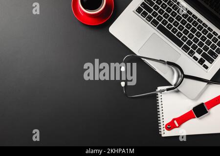 Ein Notebook auf einem schwarzen Desktop mit einer Tasse Kaffee, einem Telefon und einem wi-Fi-Schild, arbeiten Sie in sozialen Netzwerken. Draufsicht. Stockfoto