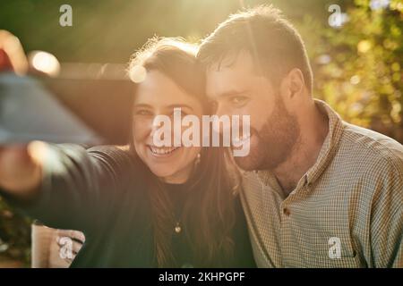 Telefon, Liebe und Paar Selfie für soziale Medien während der Flitterwochen in einem Restaurant im Freien im Sommer. Lächeln, Romantik und glückliche Frau genießen Stockfoto