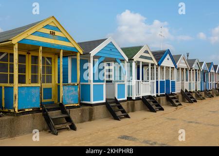 Eine Reihe farbenfroher Strandhütten unter blauem Himmel am Southwold Beach in England Stockfoto