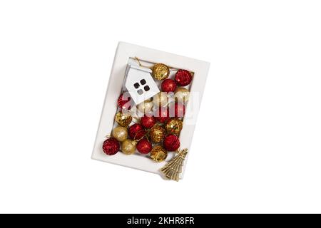 Holzrahmen mit weihnachtsdekoration aus roten und goldenen Ornamenten, goldenem Baum und Holzhaus Stockfoto