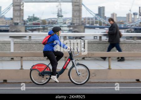 Eine Frau, die während der Hauptverkehrszeit über die London Bridge radelt, in einem Transport nach London, mietet Santander Cycles ein Fahrrad, das gemeinhin als „Boris Bike“ bezeichnet wird. Stockfoto