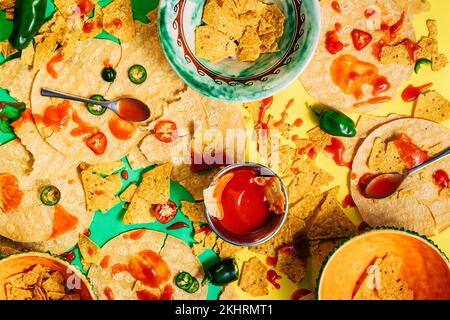 Blick von oben auf mexikanische Speisen, Tex-Mex-Speisen mit Tropfen und Flecken von Soße, mit Tortilla-Chips. Heiße Jalapenos-Sauce. Chili-Pfeffer. Reales Konzept Stockfoto