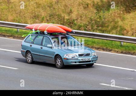 2002 grüner VOLVO V40 SE 1783cc Benzinpark transportiert Kanus auf der Dachstrecke; Fahrt auf der Autobahn M6 UK Stockfoto