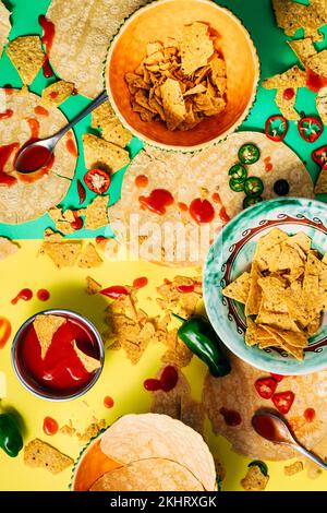 Bunte Tex-Mex-Speisen mit Tropfen und Flecken aus Soße. Blick von oben auf mexikanisches Essen mit Tortilla-Chips. Heiße Jalapenos-Sauce. Reales Konzept Stockfoto