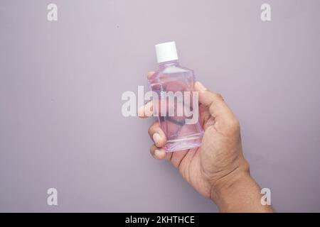 Halten Sie einen Behälter für Mundwasser mit der Hand Stockfoto