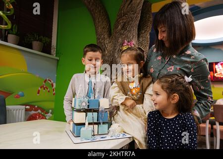 Ternopil, Ukraine- 17. November 2022: Mutter mit drei Kindern und Gefrierkuchen auf Kindergeburtstage. Stockfoto