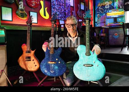 24. November 2022, Hamburg: Gitarrenhersteller Jens Ritter kniet hinter seinen Gitarren „25. Jubiläum der Magie und Freiheit“ (M) mit mehr als 11.000 Swarovski-Steinen und der Gitarre „Paraiba Velvet“ (r) an der Zwick St. Pauli. Ritter präsentiert einige seiner Instrumente im Kult-Pub "Zwick" in Hamburg-St. Pauli. Seine elektrischen Gitarren und Bässe werden nicht nur von Musikern, sondern auch von Sammlern und Museen gekauft. Seine Instrumente sind auch im Metropolitan Museum of Art (New York) im Smithsonian American Art Museum (Washington, DC) und im Technoseum (Mannhe) ausgestellt Stockfoto