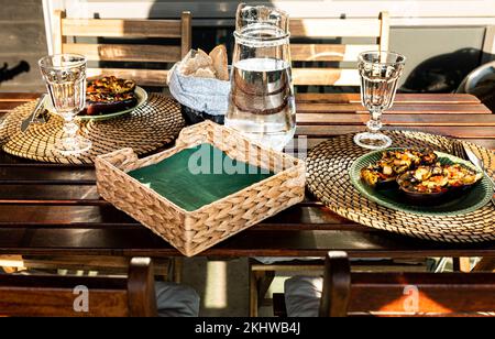 Mahlzeit mit gefüllten Auberginen und hausgemachtem Brot im Freien in der Sonne. Köstliches Gericht auf einem Holztisch mit gefüllten Auberginen und handgemachtem Brot Stockfoto