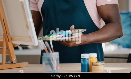 Ein gereifter, erfahrener 50s-jähriger afrikanischer Maler, der im Kunststudio ein Bild mit Acrylöl auf Leinwand malt, sorgt für verärgerte Gefühle Stockfoto