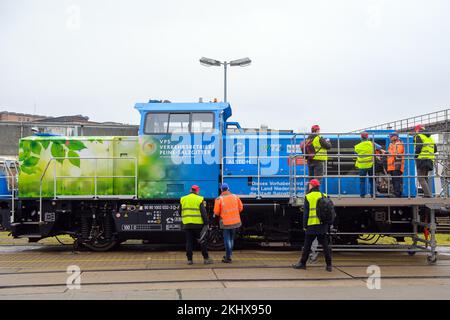 24. November 2022, Sachsen-Anhalt, Stendal: Medienvertreter und Mitarbeiter von Alstom stehen vor einer wasserstoffbetriebenen Rangierlokomotive. Das Unternehmen sieht ein beträchtliches Potenzial bei der Umstellung von dieselbetriebenen Rangierlokomotiven auf Wasserstoffantrieb. In Deutschland sind etwa 1000 Diesel-Rangierlokomotiven in Betrieb und in ganz Europa etwa 4000. Bisher wurden Hybridlokomotiven mit Batterie- und Dieselantrieb betrieben; in Zukunft werden sie mit Batterie- und Wasserstoffantrieb betrieben. Eine Lokomotive emittiert etwa 150 Tonnen CO2 pro Jahr, während ein modernisierter Shunti Stockfoto