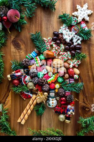 Festliche Süßigkeiten in Form eines Baumes, umgeben von Grün. Stockfoto