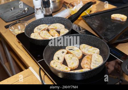 Zwei Bratpfannen mit getoasteten Brotscheiben auf dem Herd Stockfoto