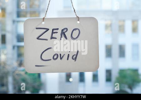 Kein Covid-Zeichen am Fenster, Bürogebäude hinten. Stockfoto