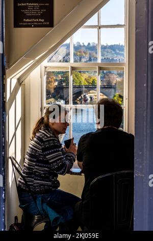 Ein paar Plauderchen beim Kaffeetrinken im Pulteney Bridge Coffee Shop in Bath Spa, Somerset, England, Großbritannien Stockfoto