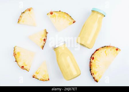 Ananas-Smoothie in Flaschen mit Zutaten. Gesunde vegane Rohkost. Draufsicht, flach liegend. Stockfoto